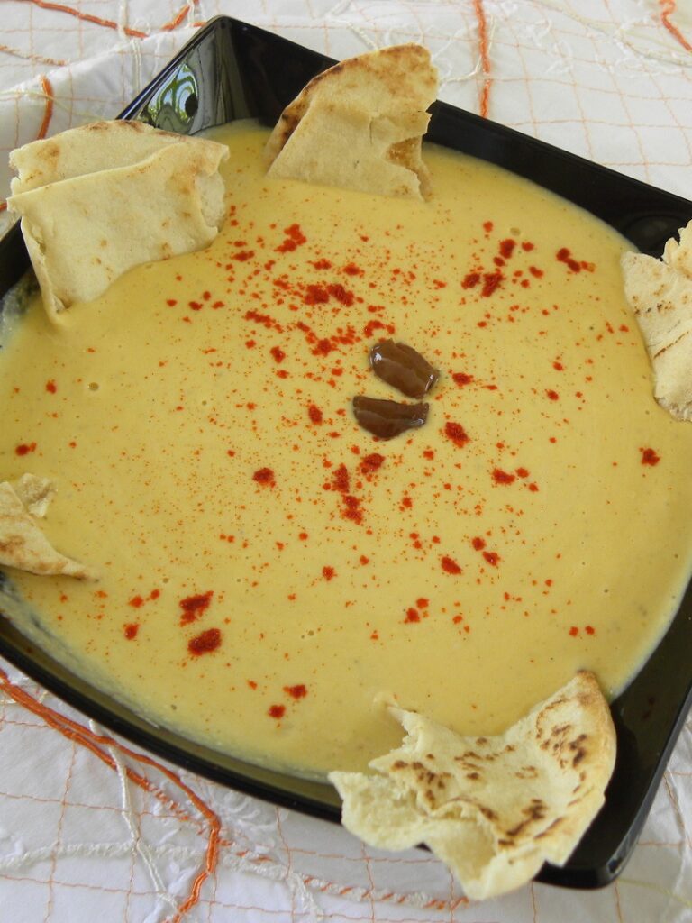 Hoummous in a black plate with pita chips image